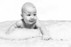 On a soft carpet Baby Oscar smiling lying on their stomach Black and white