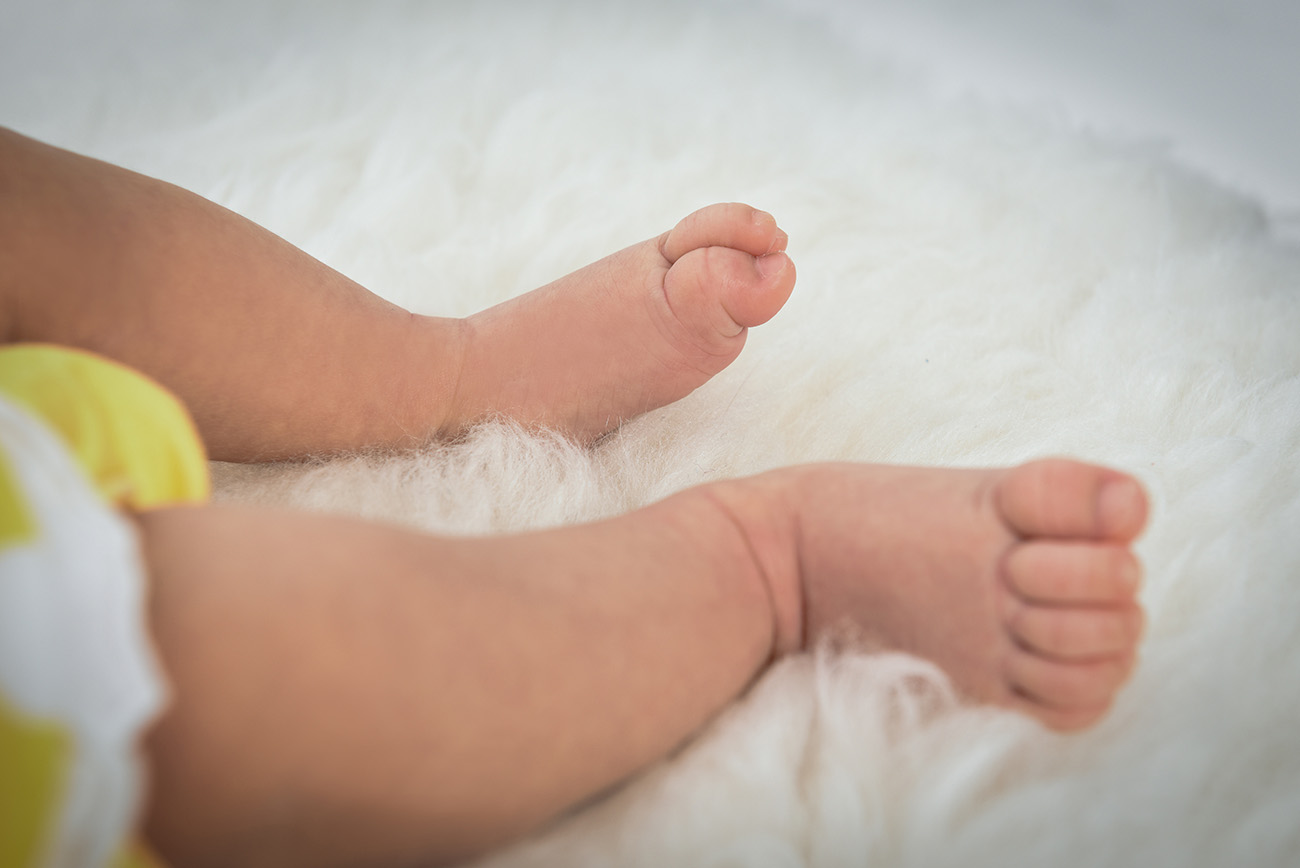Half cropped with little legs and feet of the baby placing on a fuzzy blanket