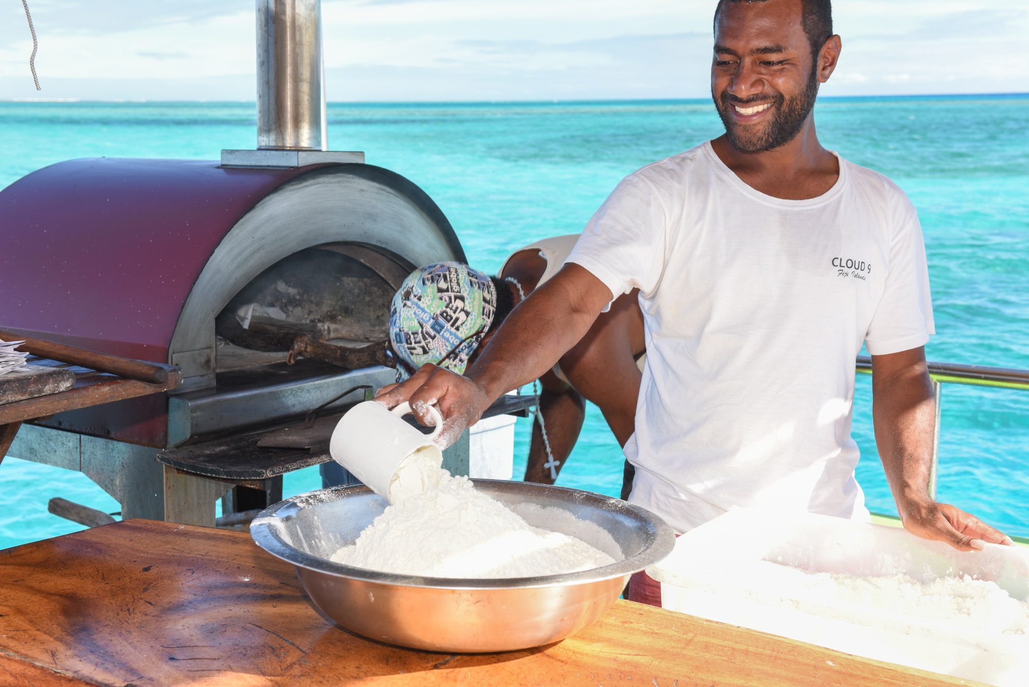 On the bar islnd a Cloud 9's member preparing the flour for the pizza dough with turquoise sea in the background