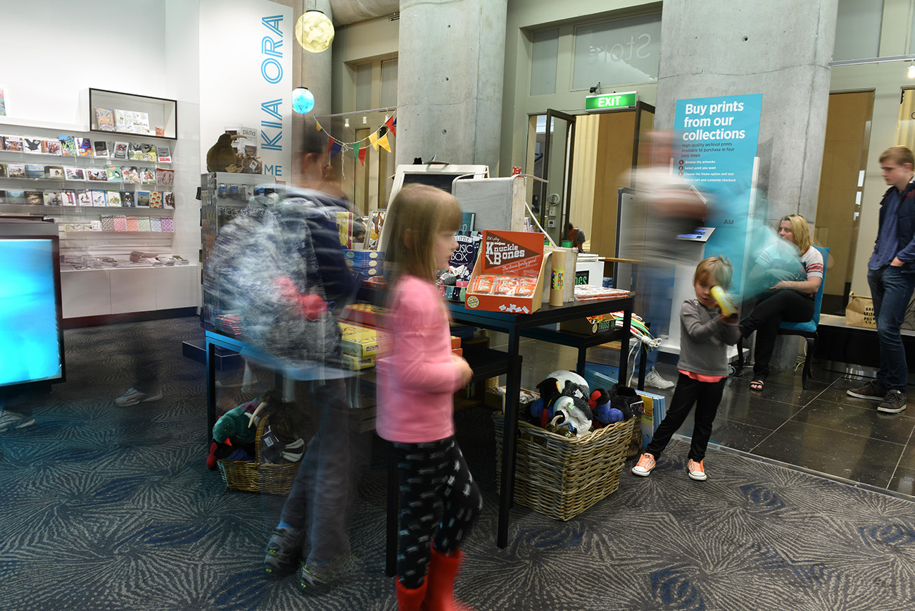 In the Auckland museum shop children blurred playing with objects arround a table