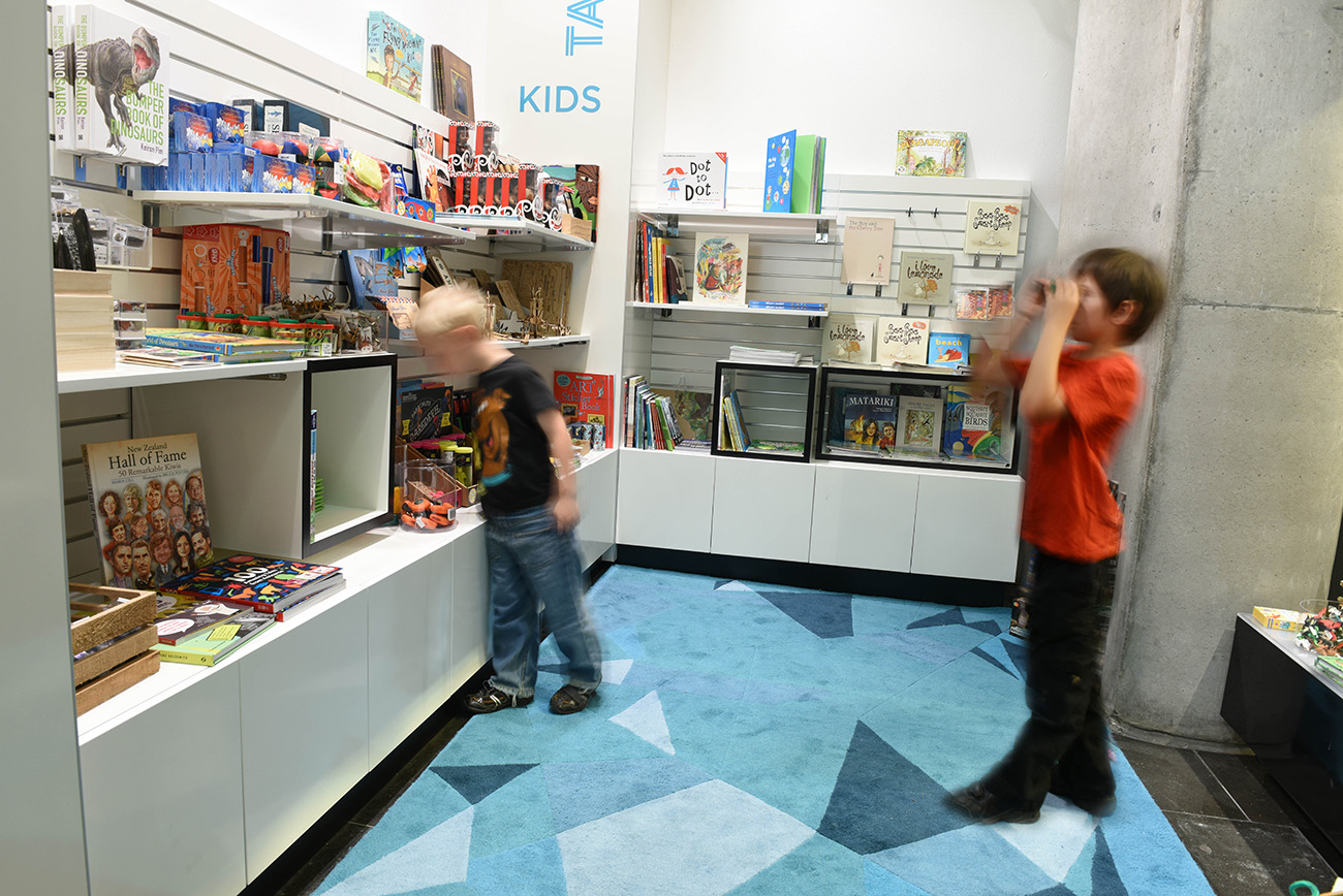 In the children part of the auckland museum shop two young children blurred playing with different objects