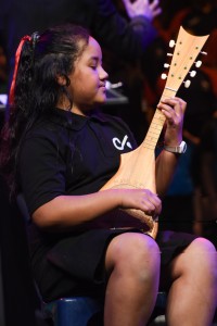 A young girl playing a traditional ukulele of Pacific Islands