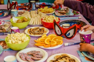 Fod on the birthday table : cakes, oranges, pop corns, spider man mask, sandwiches