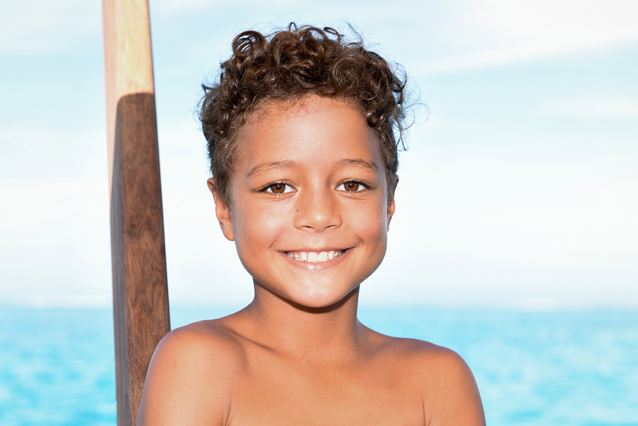 A cute little boy smiles at the camera aboard Cloud 9 in Fiji