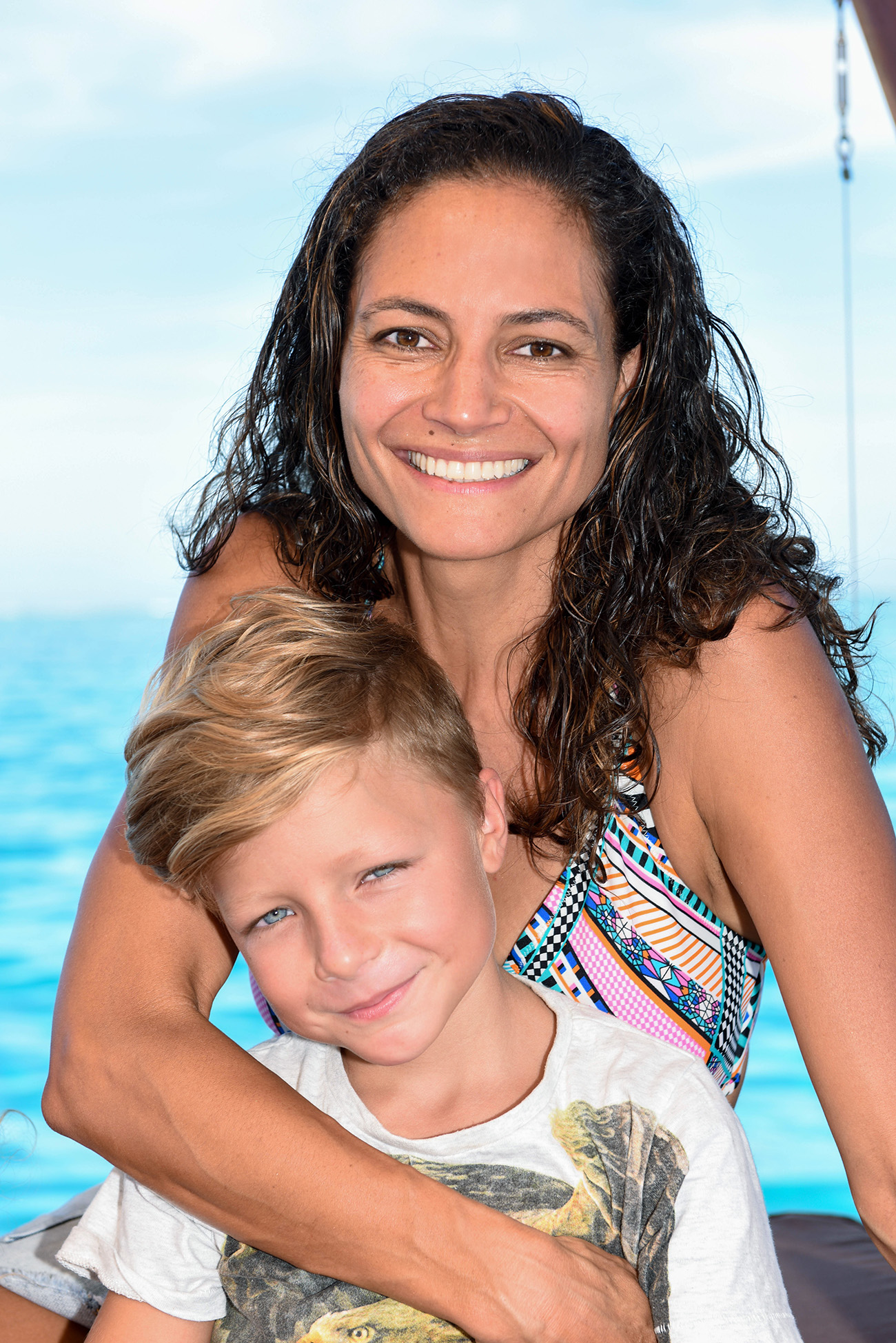 Mother and son smile at the camera aboard Cloud 9 in Fiji