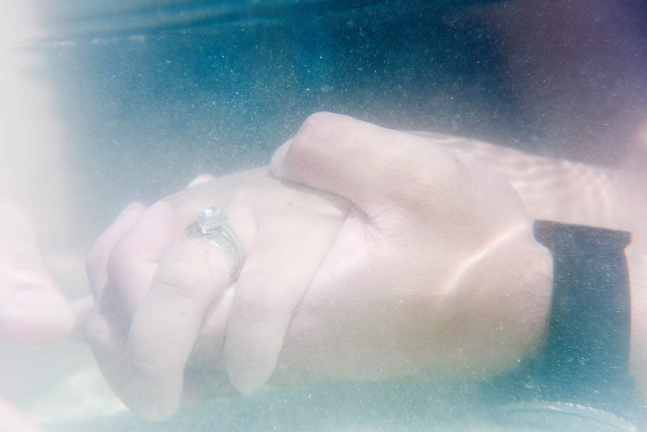 underwater photography of a couple holding hands with the engagement ring in Fiji by Anais Photography