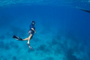 man underwater snorkeling in the ble ocean in Fiji by Anais Photography