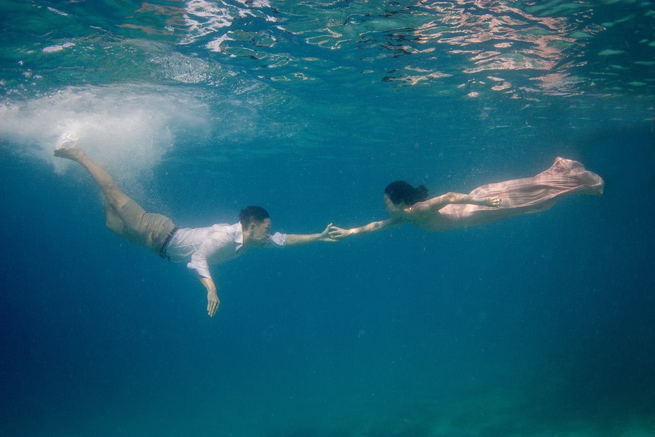 Couple reaching to each other underwater in Fiji