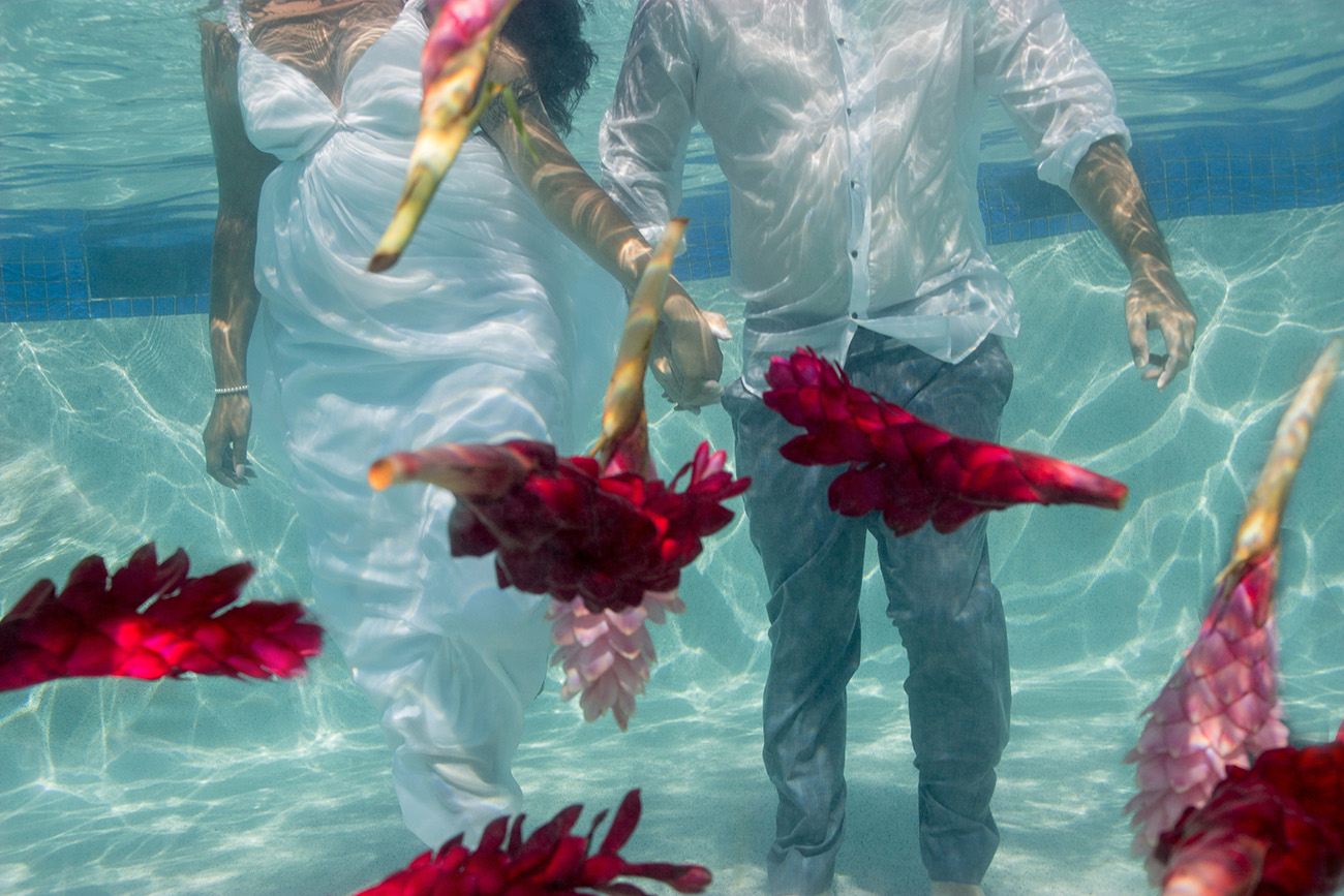 couple holding hand underwater with flowers floating in the swimming pool at the Westin resort in Denerau Fiji