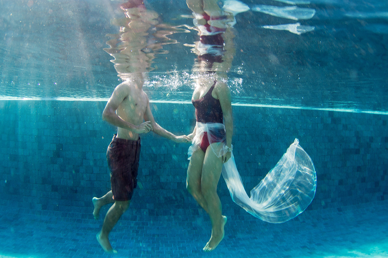 couple holding hands underwater with their reflection on the top in Fiji by Anais Photography