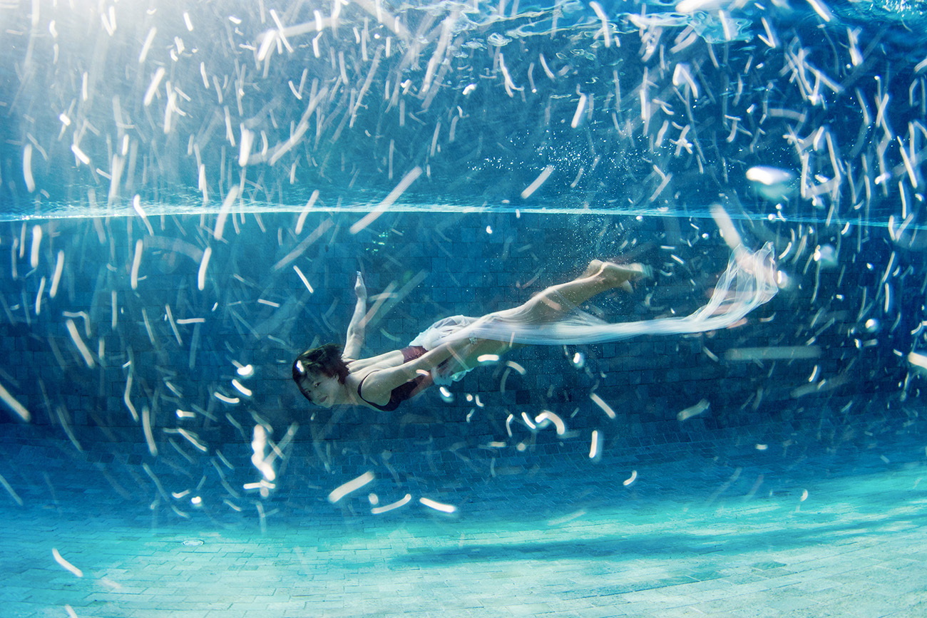 underwater woman swimming in the pool with bubbles in Fiji by Anais Photography