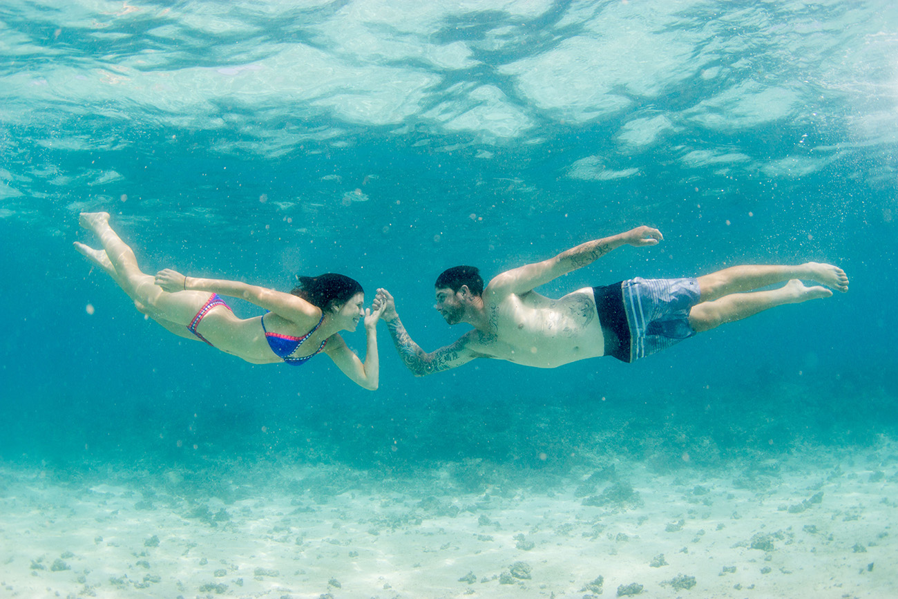 Couple reaching towards each others underwater Cloud 9 in the Mamanuca islands in Fiji