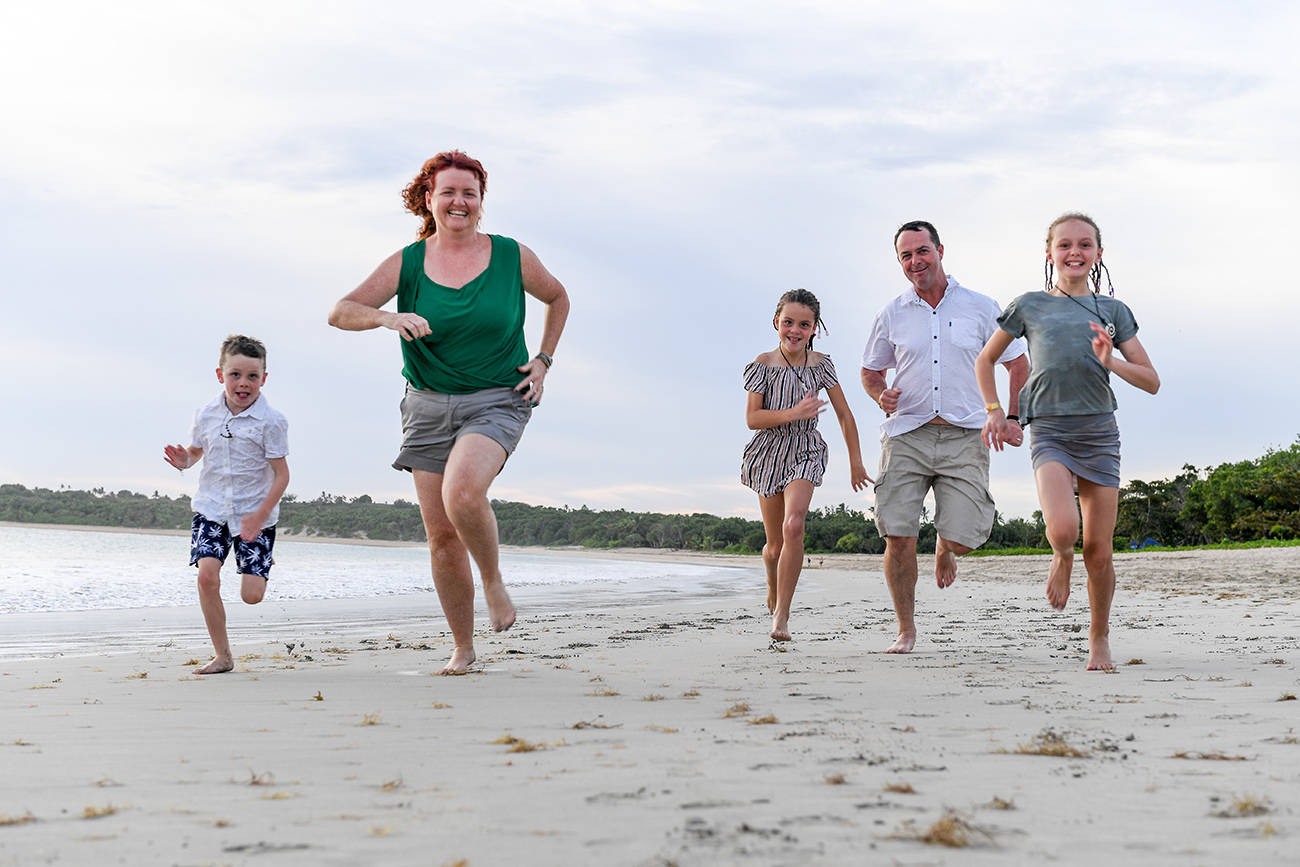 Mum dad and children running on beach in family photoshoot Fiji