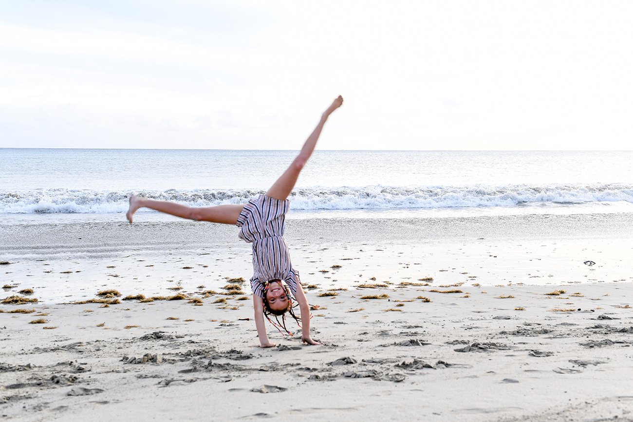 Young girl does cartwheels on the beach
