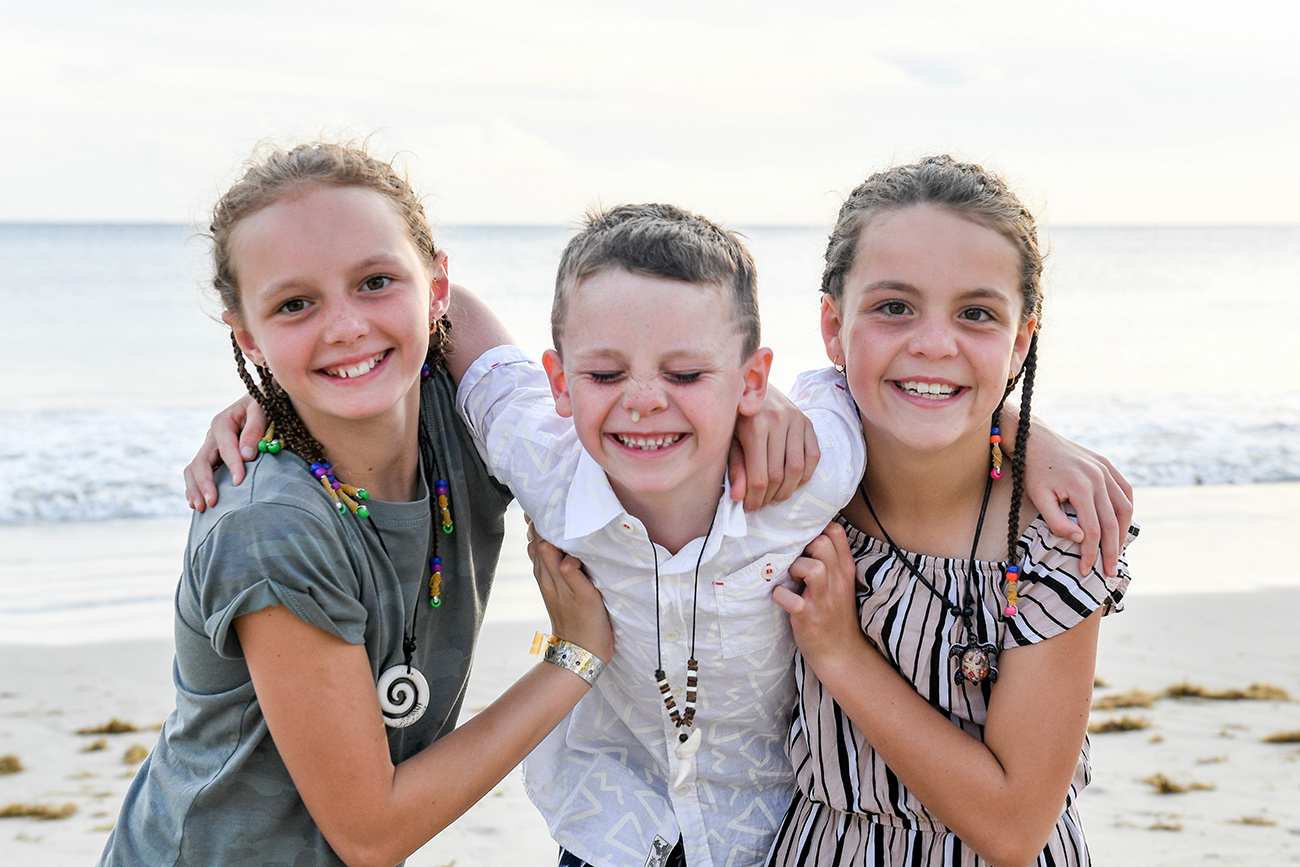 Cute young sisters and brother grin in family photography Natadola beach