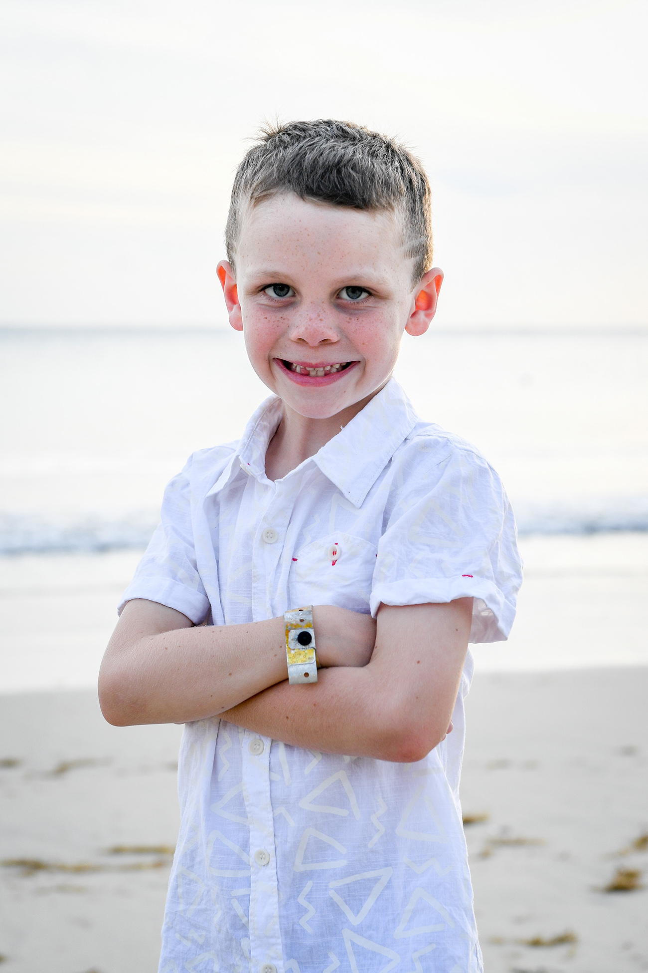 Cute young boy smiles at the camera in beach family photoshoot