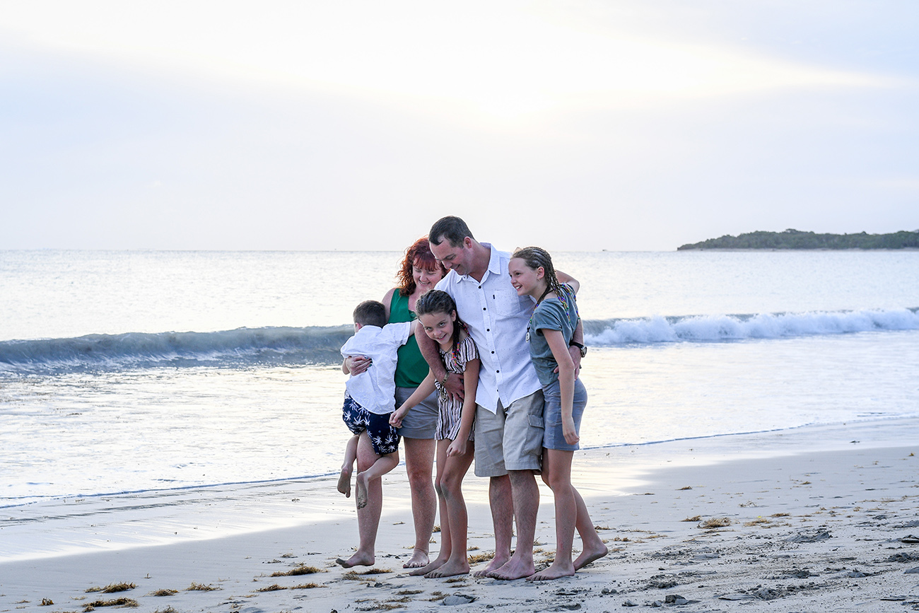 Wideshot of family hugging and cuddling on the beach in Fiji family photoshoot
