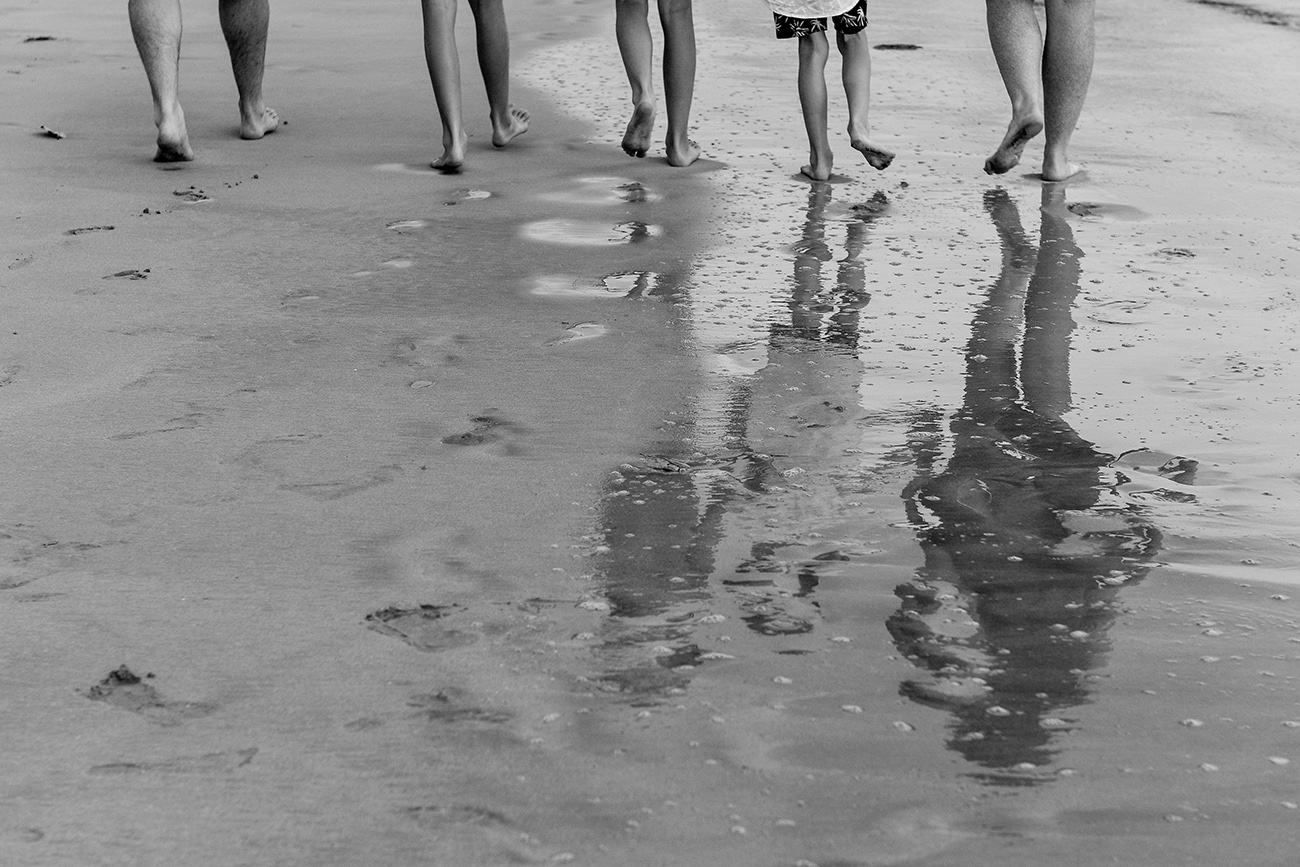 Black and white photo of feet of family walking on the sand in Natadola Fiji