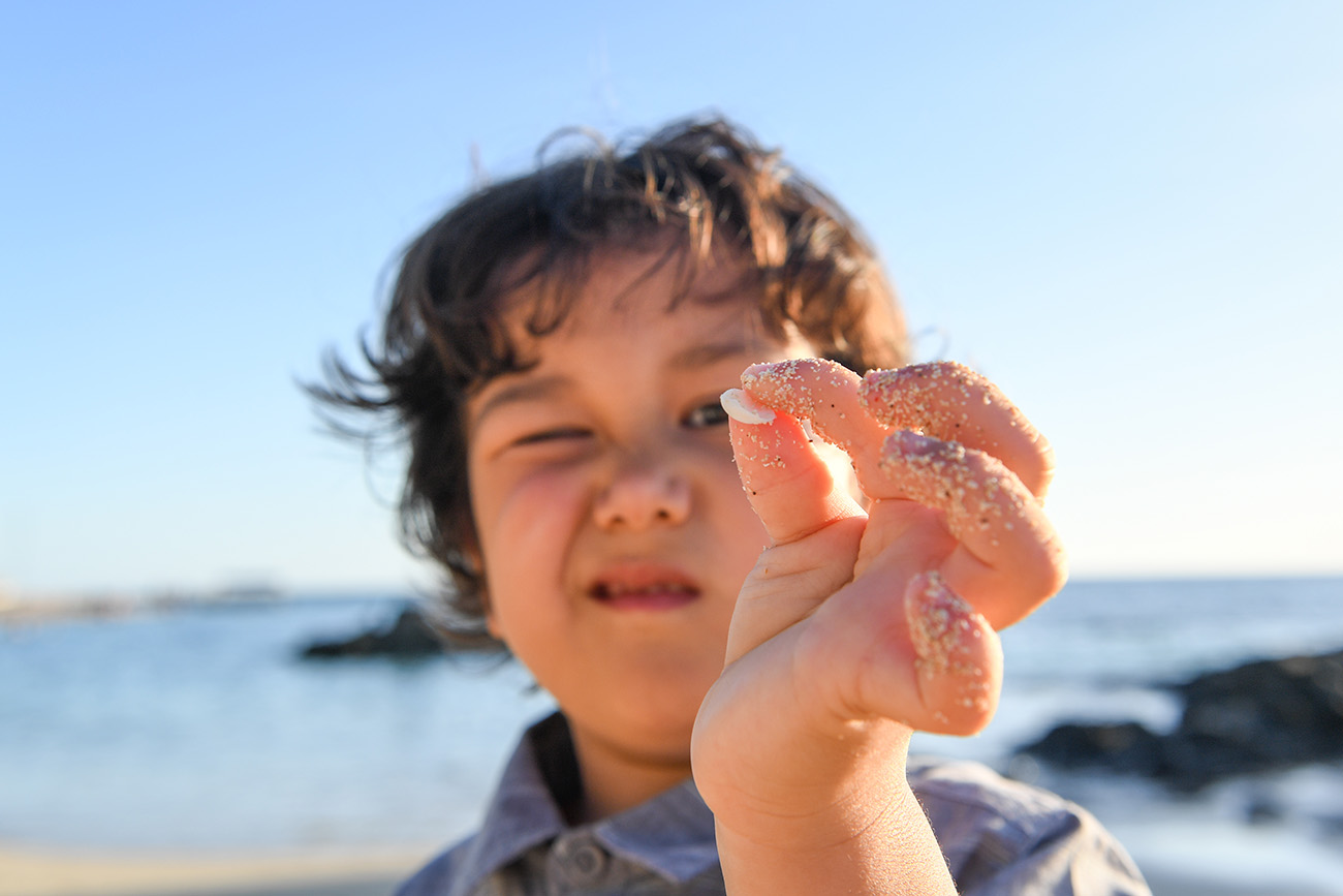 Young boy picks up sea shell in Fiji