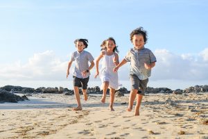 3 cute siblings running on Fiji sandy beach in Malolo village