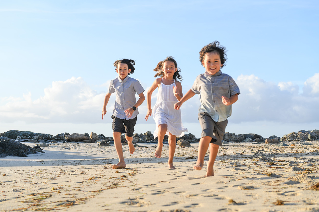3 cute siblings running on Fiji sandy beach in Malolo village