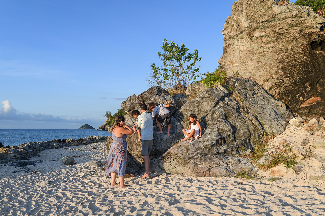 Cute family climb rocks on the sandy beach in Malolo Fiji