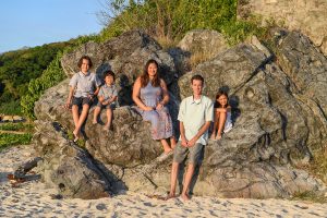 Wideshot of family seated on huge boulder posing at family photo session in Fiji