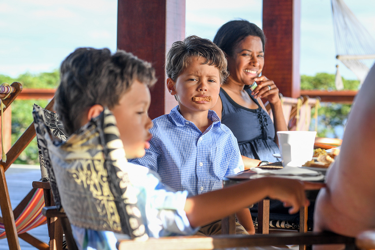 Triplet boys make fun with their toast at the breakfast table in Fiji