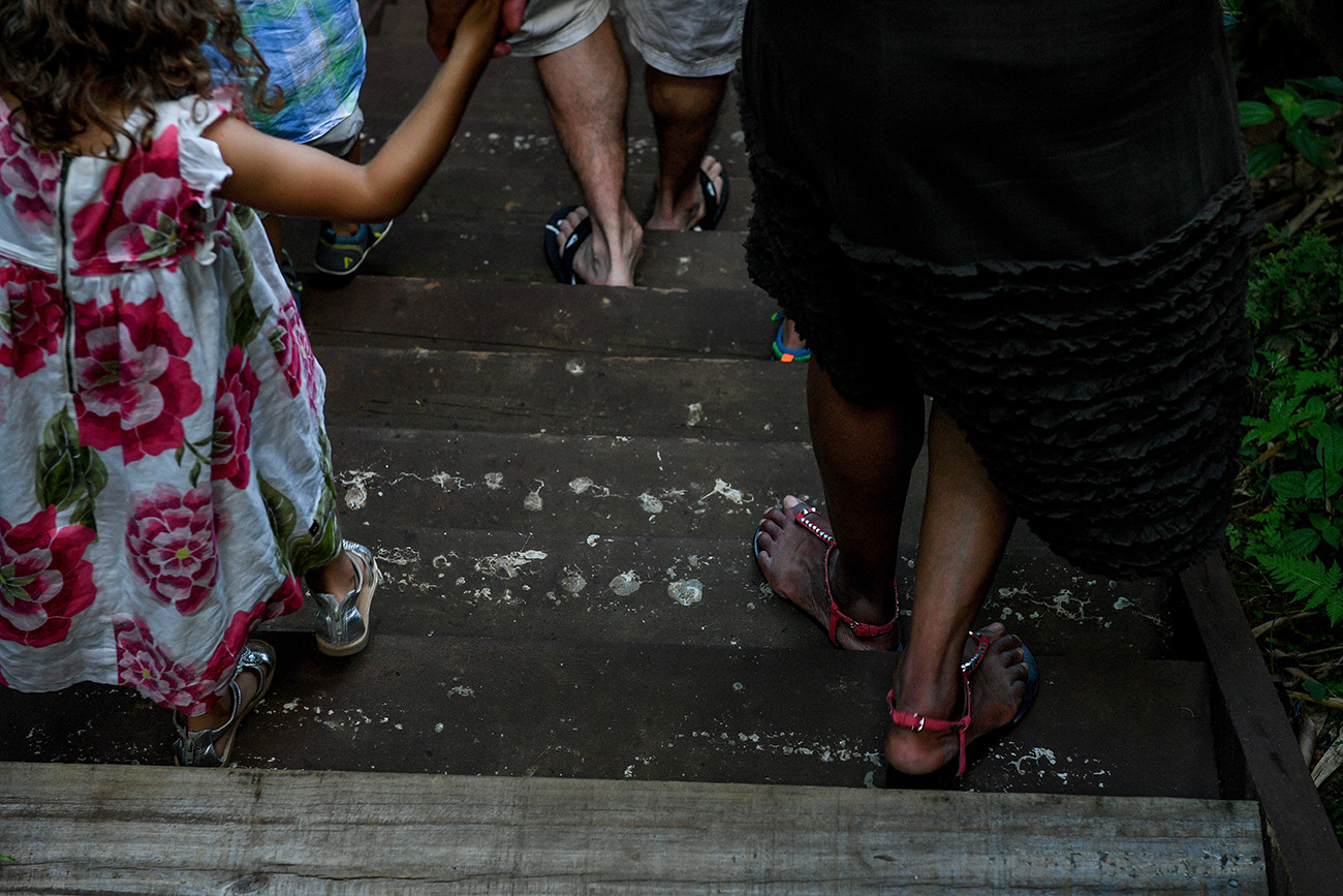 Family feet as they walk on bridge toward tropical rainforest