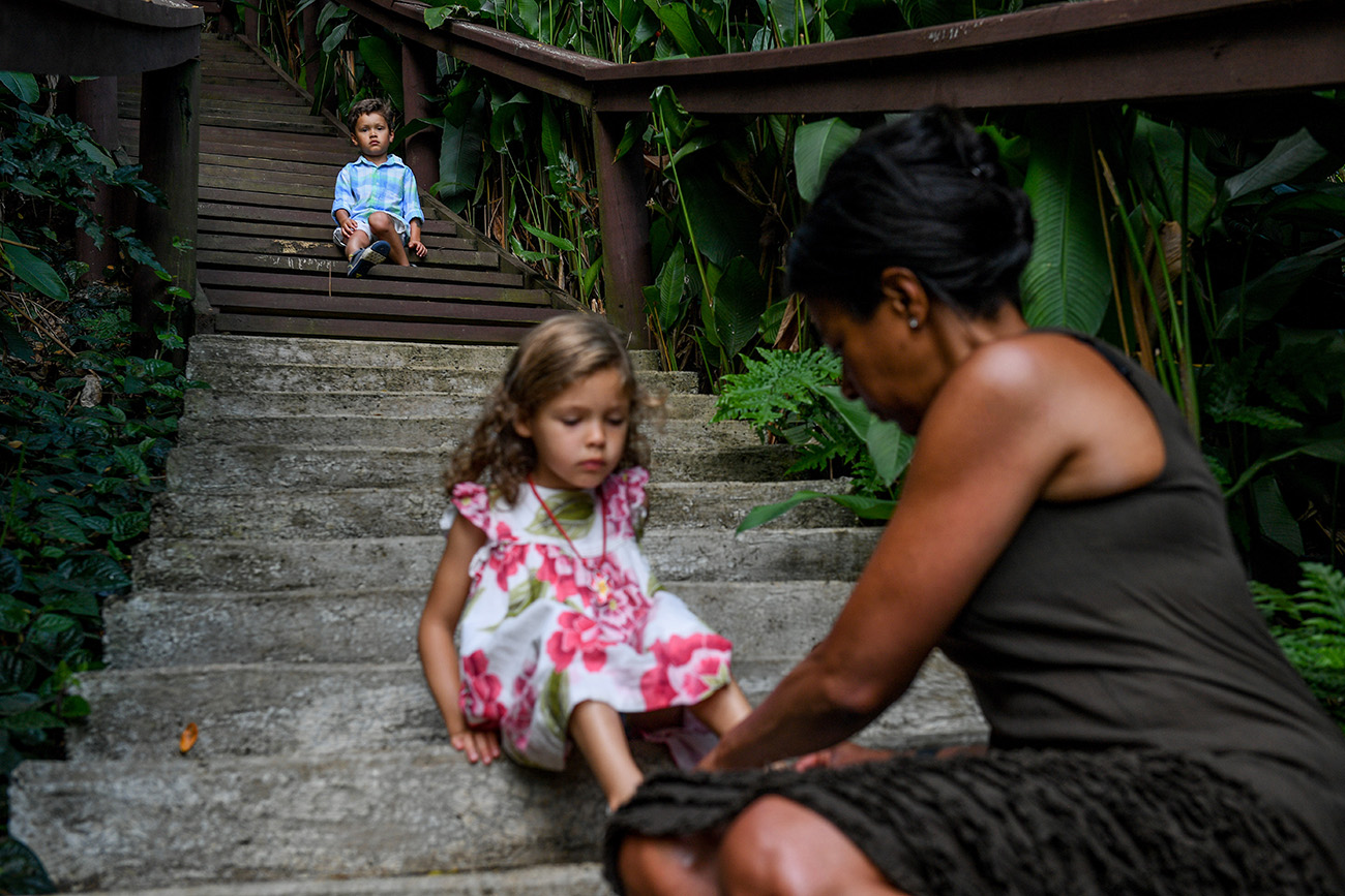 Mom puts shoes on her daughter at bottom of steps during family vacation