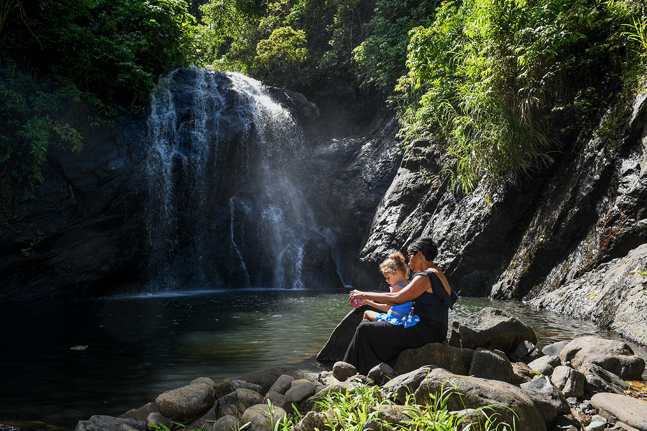 Mother and daughter seated by the river watching waterfall in Fiji