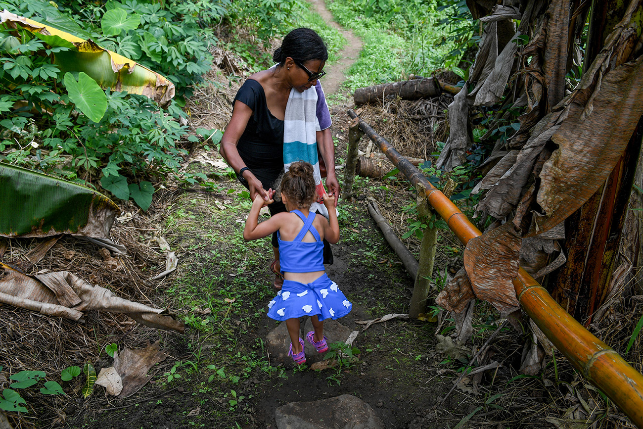 Mom carries daughter over rock in Fiji rainforest