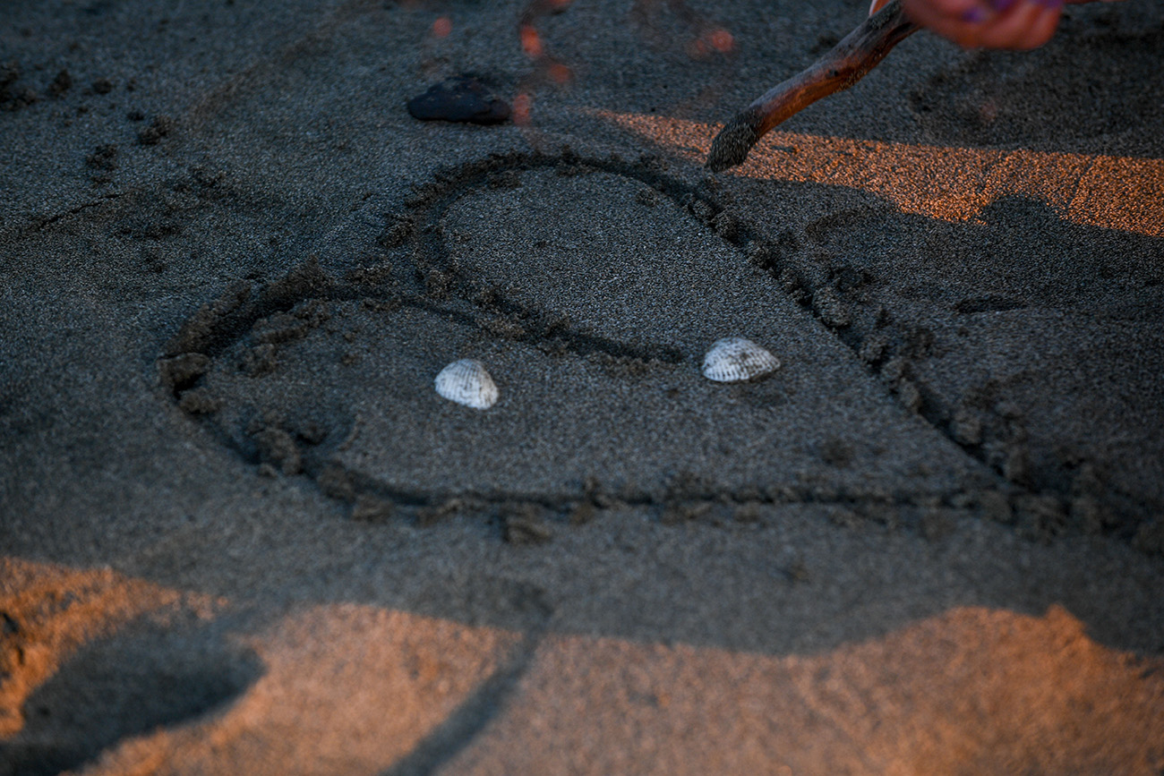 The family draws a simple love heart in the sand