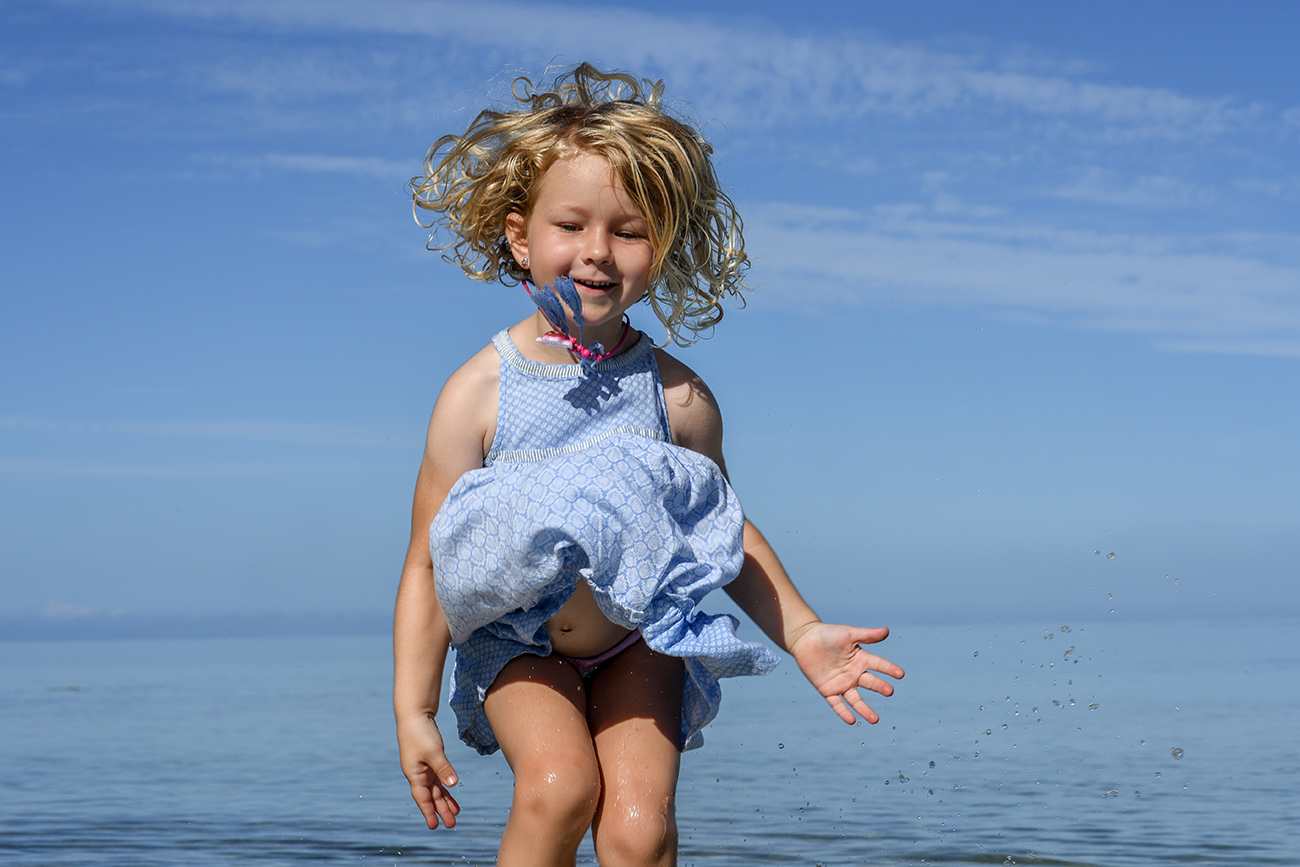 Cute girl jumps into the air in the sea