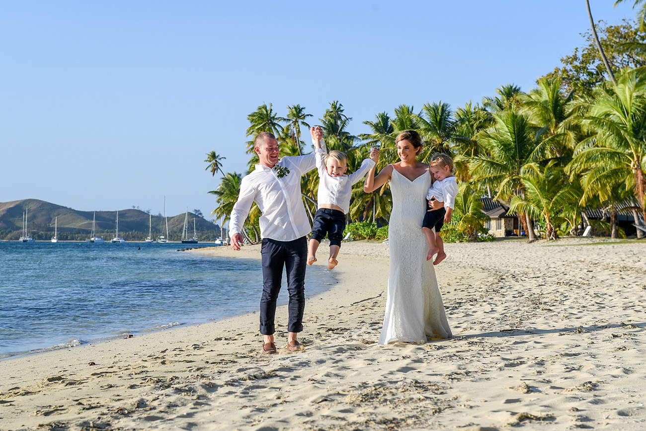 Mom and dad lift their son in all white family photoshoot in Fiji
