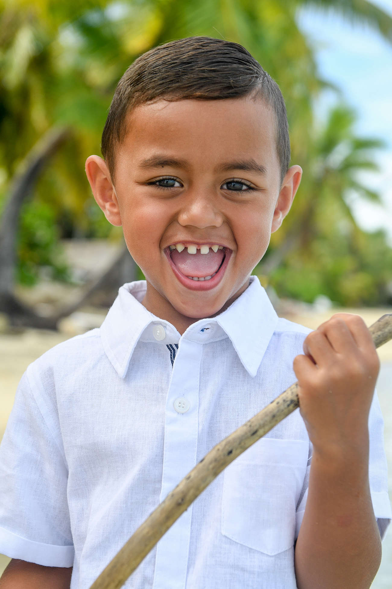 Cute Polynesian boy with milk teeth playing with a stick