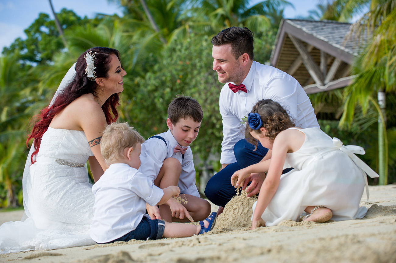 Newly married couple build sand castles with their babies in the sand