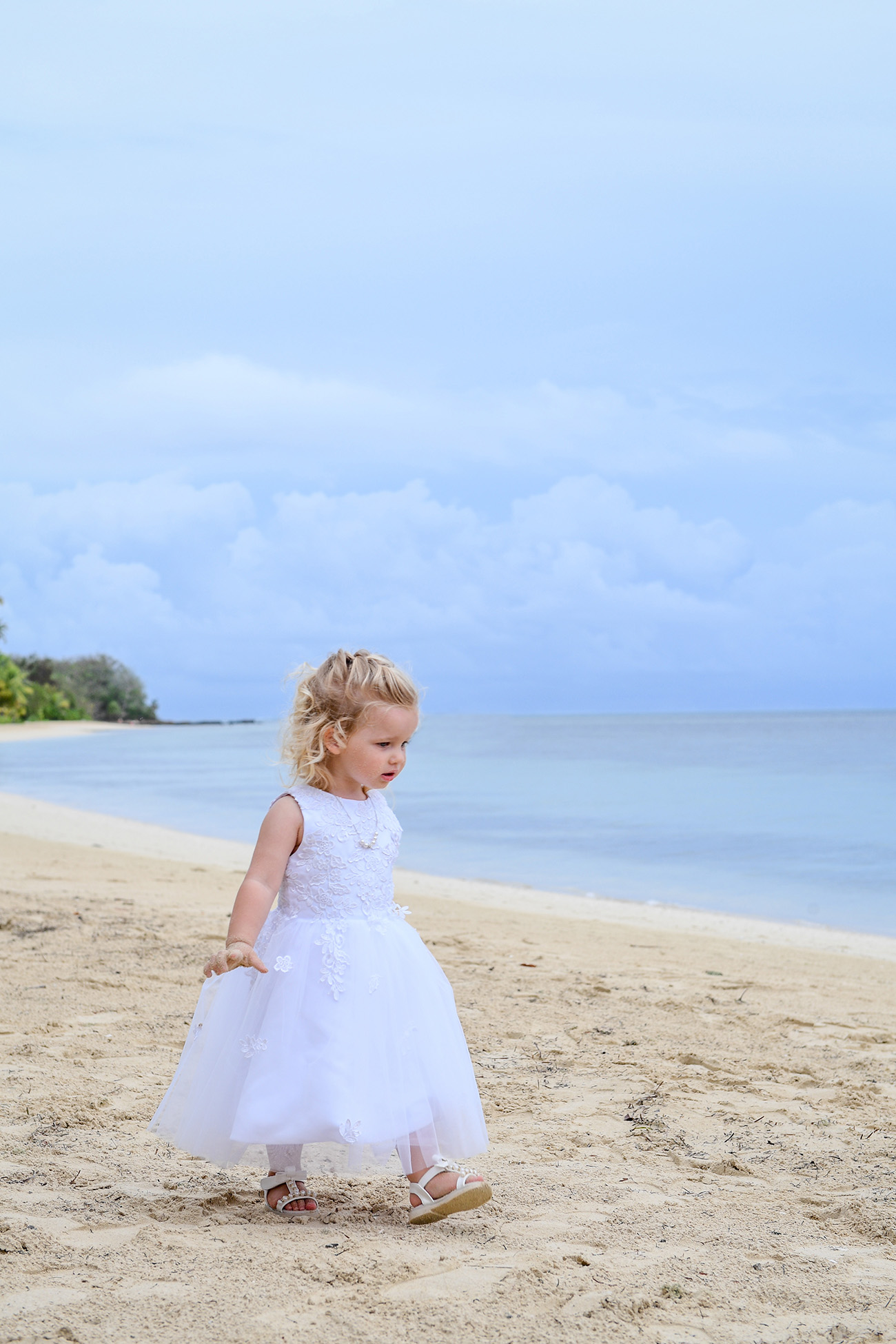 Stunning baby girl in all white strolling on Fiji water