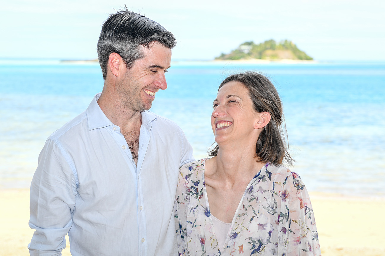 The happy couple laugh while standing at the stunning beach at Malolo Island