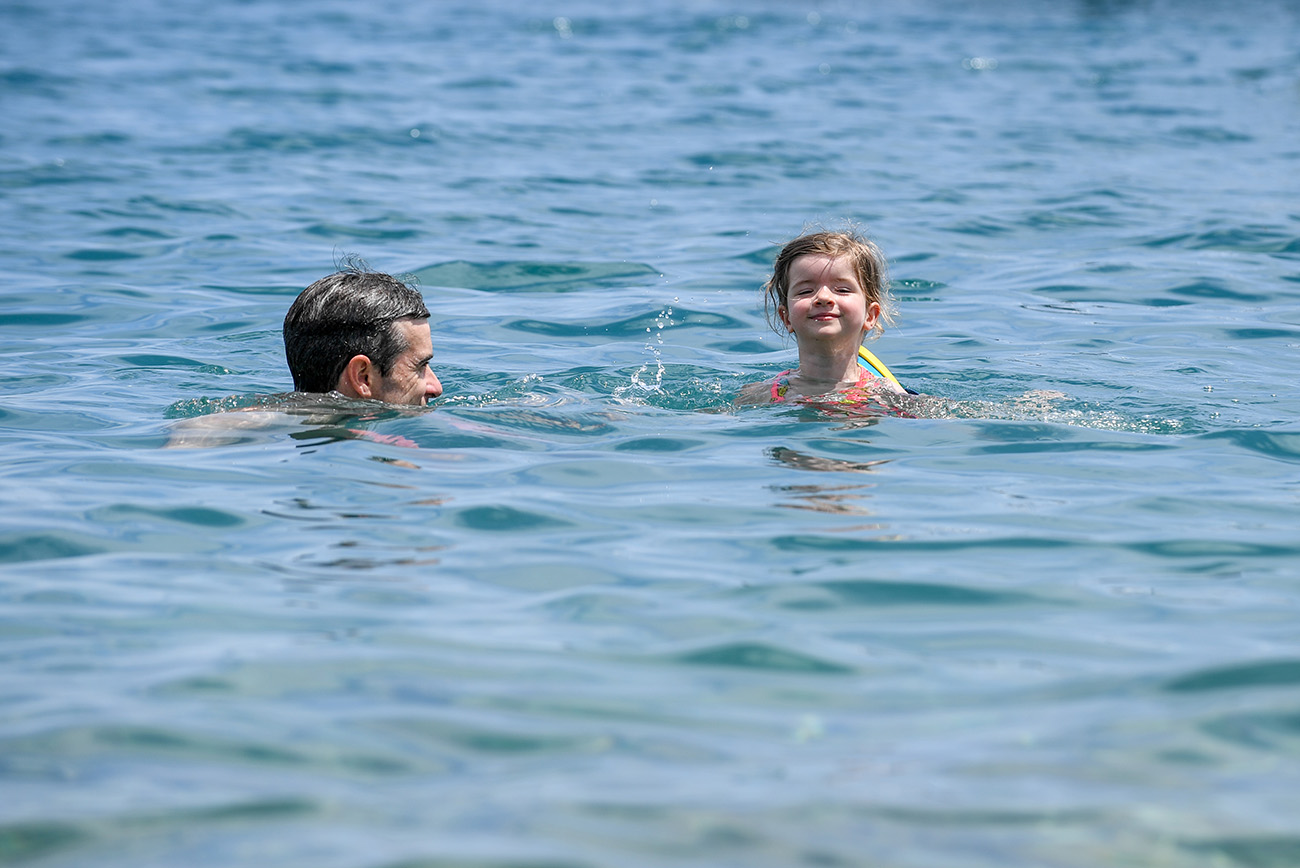 The baby paddles with her father in the ocean