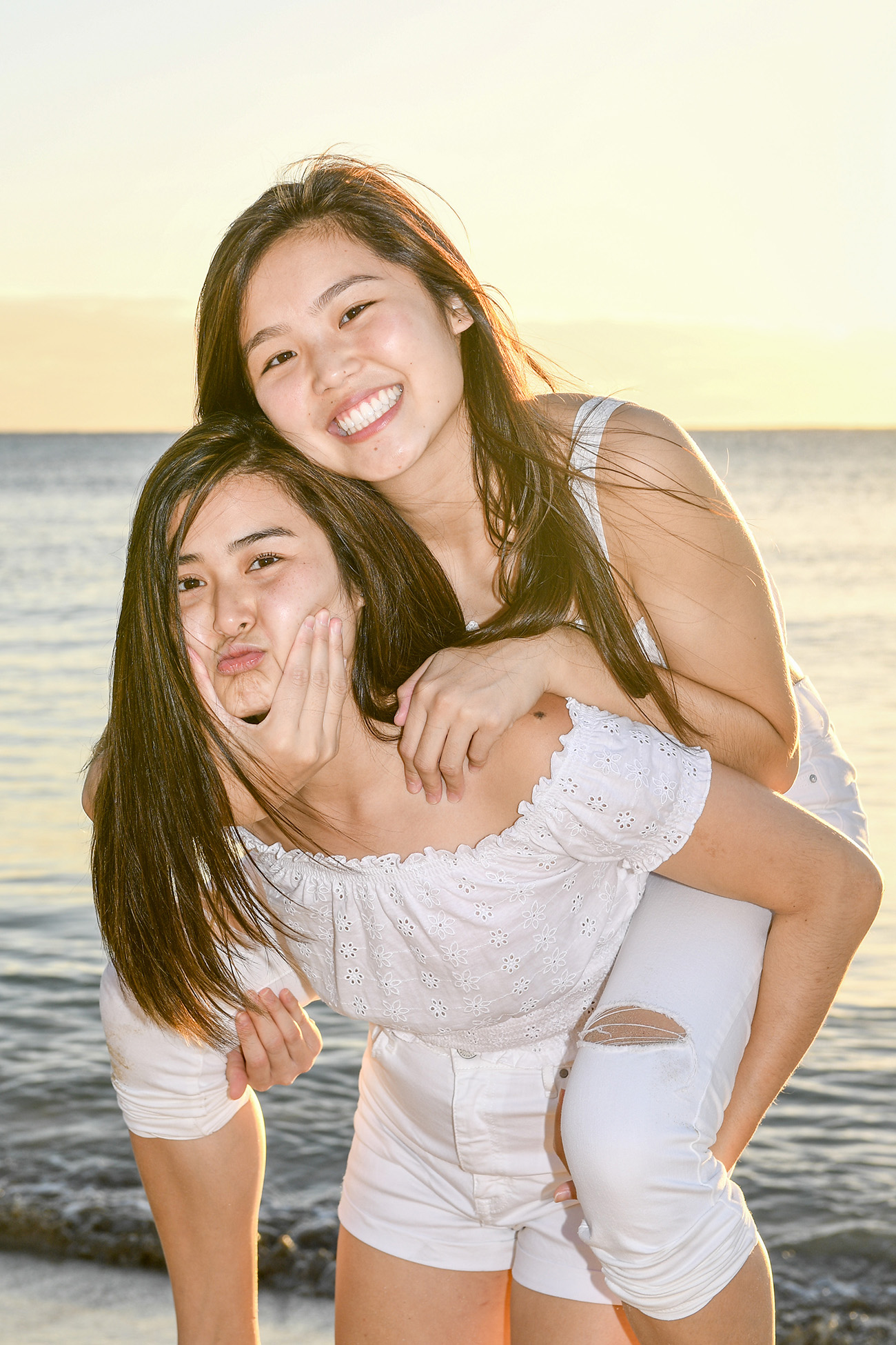 Asian sisters goof on the beach in the sunset
