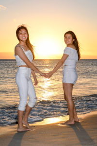 Sisters hold hands against the fiery Fiji sunset