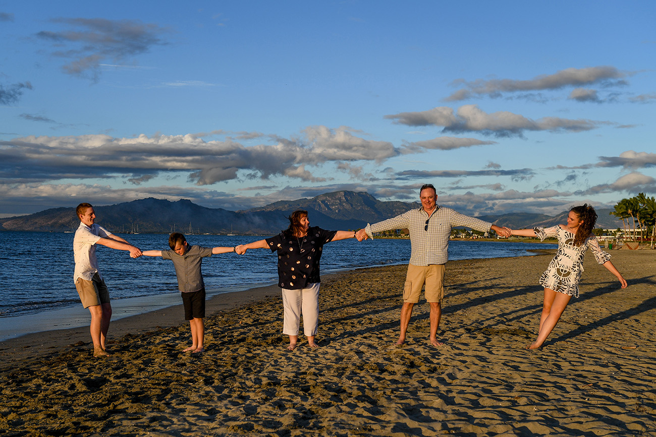 Family holds hands on the beach at Denarau Fiji