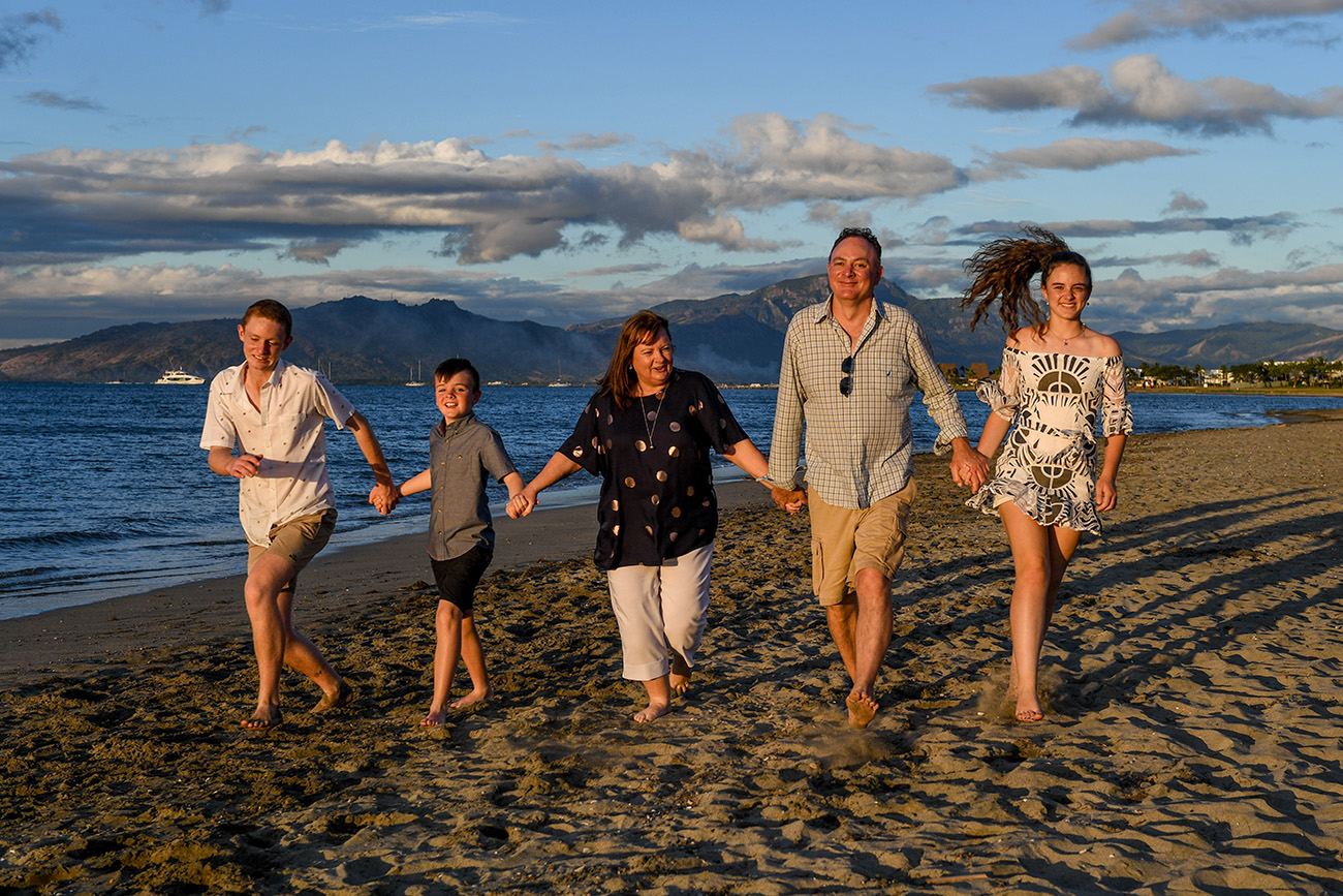 Family holds hands on the beach at Denarau Fiji