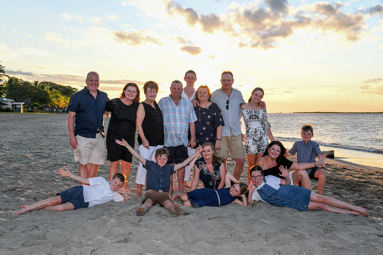 An extended caucasian family poses on the beach at Natadola