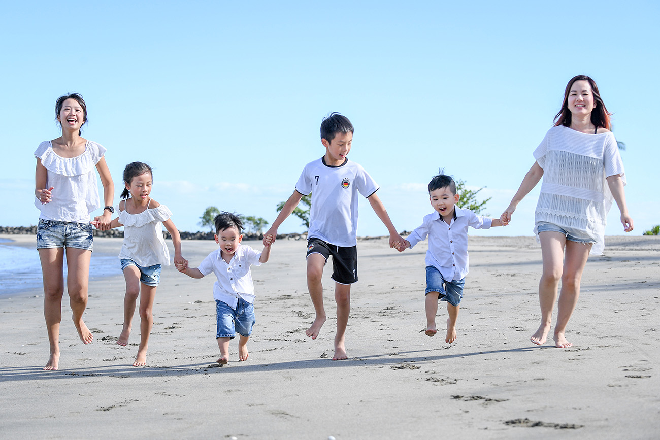 Cute asian family hold hands and run on the beach at Natadola Fiji