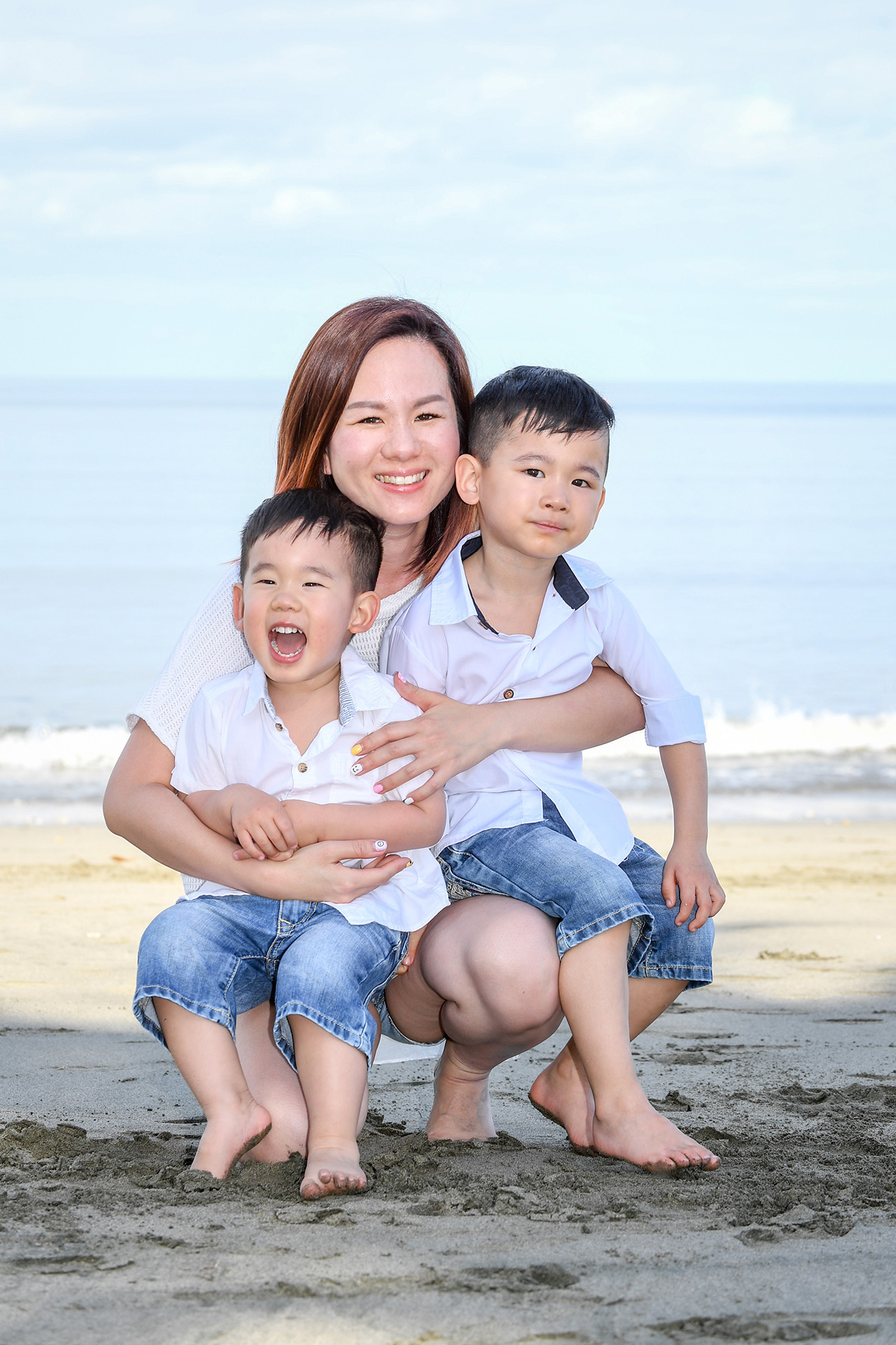 Mother cuddles her two sons on Natadola beach