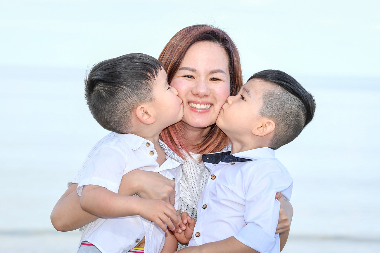 Two sons kiss their mother on the cheek