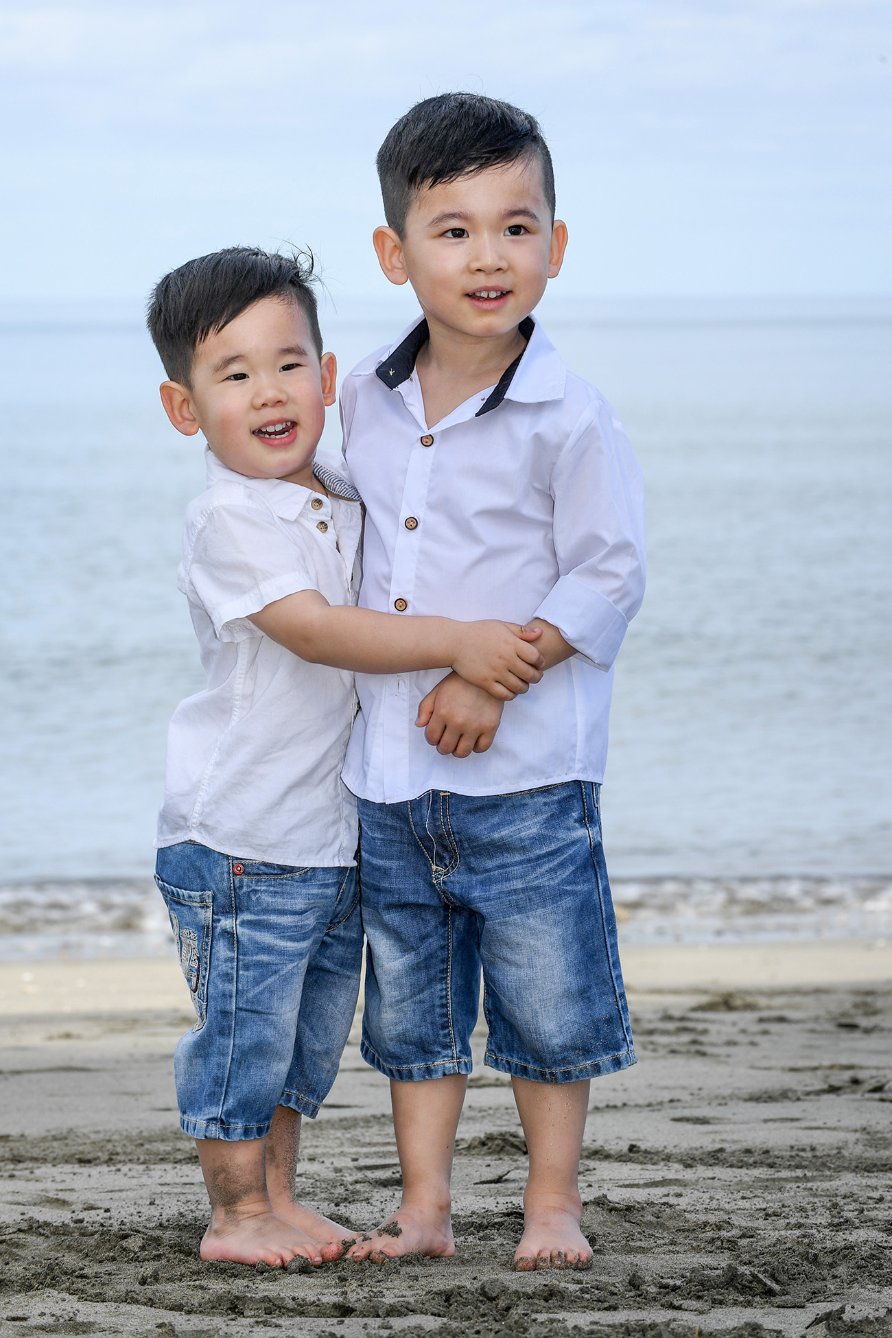 Two asian baby brothers hug while at the beach at Natadola Fiji