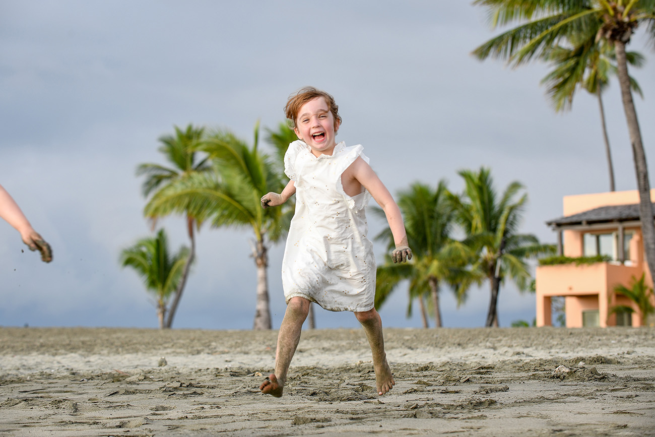 A happy boy leaps and jumps on the beach against palm trees at Natadola beach